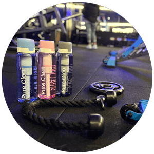 Pure Clear® active water filter bottles in a gym setting, showcasing advanced filtration technology beside gym equipment and weights.