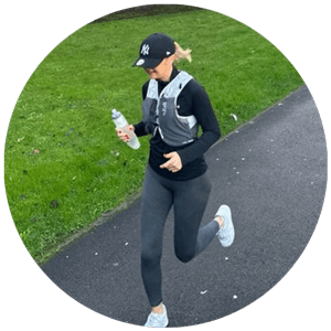 Woman jogging on a path, holding a water bottle, wearing a hydration vest, showcasing active lifestyle and Pure Clear Filters' water filtration products for outdoor activities.